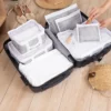 Ein offener Koffer mit einem sechsteiligen Organizer-Set in Weiß und Grau, ideal zur strukturierten Aufbewahrung von Kleidung und Accessoires.