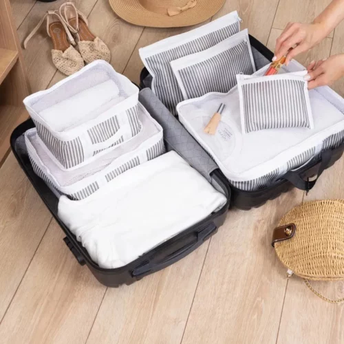 Ein offener Koffer mit einem sechsteiligen Organizer-Set in Weiß und Grau, ideal zur strukturierten Aufbewahrung von Kleidung und Accessoires.