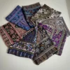 Eine Sammlung von Retro-Schals mit bunten Paisley- und Ethnomustern, kunstvoll auf einer weißen Oberfläche arrangiert.
