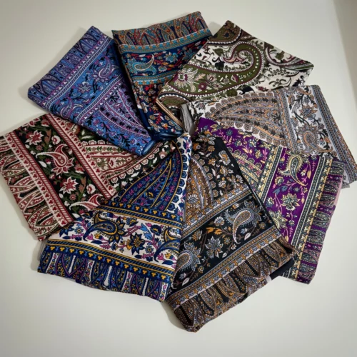 Eine Sammlung von Retro-Schals mit bunten Paisley- und Ethnomustern, kunstvoll auf einer weißen Oberfläche arrangiert.