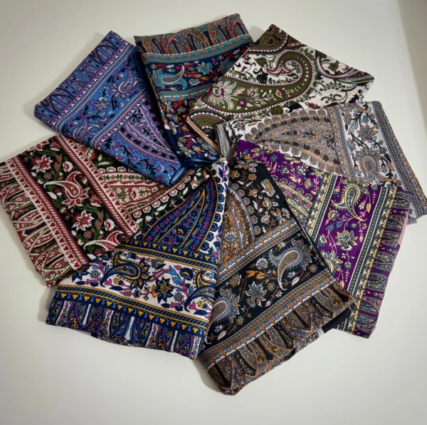 Retro-Schals mit farbenfrohen Ethnomustern – Stilvolle Vielfalt Eine Sammlung von Retro-Schals mit bunten Paisley- und Ethnomustern, kunstvoll auf einer weißen Oberfläche arrangiert.