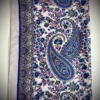Ein eleganter Baumwollschal mit blauem Paisley-Muster und floralen Verzierungen auf hellem Hintergrund.
