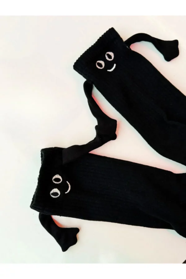 Schwarze Freundschaftssocken mit lachendem Gesicht und magnetischen Händen – Lustiges Geschenk Ein Paar schwarze Socken mit lachendem Gesicht und angenähten Armen, die sich an den Händen halten.