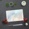 Glas Schneidebrett in Marmoroptik auf einer dunklen Arbeitsfläche, umgeben von frischen Tomaten, Kräutern, Knoblauch, einem Messer und einem Küchentuch.