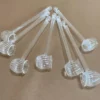 Transparente Kunststoff-Teelöffel mit gerilltem Design, auf einer braunen Oberfläche arrangiert