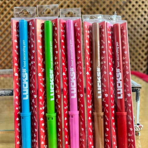 Lebensmittelfarb-Stifte in verschiedenen Farben in transparenter Verpackung auf einem Holztisch