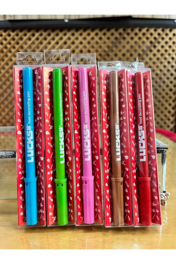 Lebensmittelfarb-Stifte in verschiedenen Farben in transparenter Verpackung auf einem Holztisch