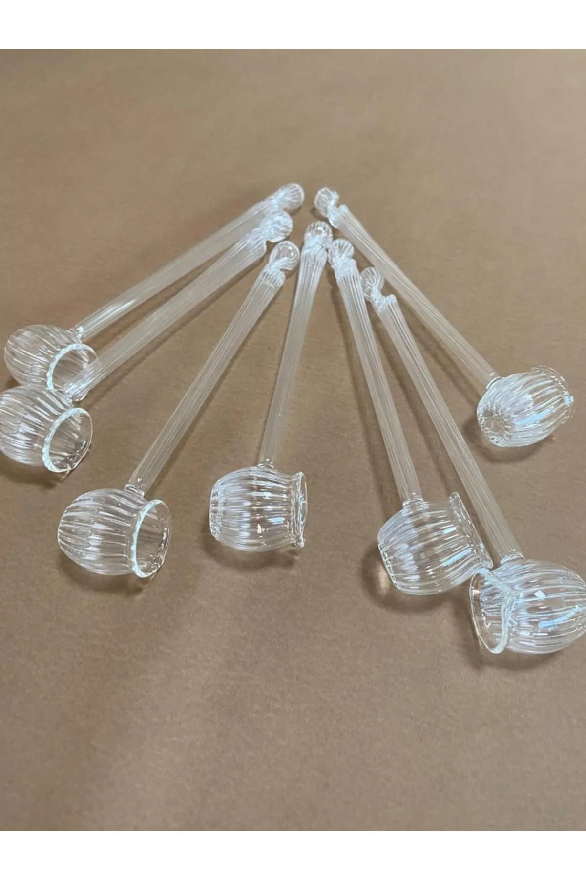 Transparente Kunststoff-Teelöffel mit gerilltem Design, auf einer braunen Oberfläche arrangiert