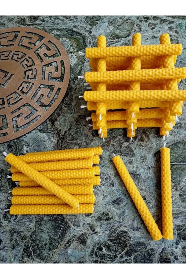 Handgerollte Wunschkerzen aus natürlichem Bienenwachs, gestapelt und lose auf Marmorplatte arrangiert