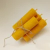 Vier handgerollte Bienenwachskerzen, mit Naturfaserband gebunden, auf hellem Hintergrund